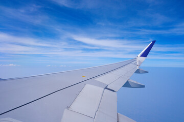 Obraz premium Photo of airplane wing with clouds background, horizon line and clear blue sky