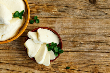 Fresh halloumi cheese on a parchment on dark rustic background, top view, copyspace