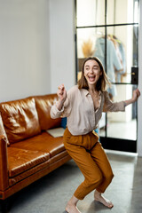 Obraz premium Happy woman jumps from the brown sofa to the floor at living room. Jump for joy and good news