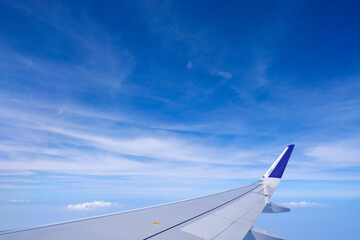Fototapeta premium Photo of airplane wing with clouds background, horizon line and clear blue sky