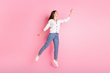 Full length photo of happy charming young lady jump up reach empty space isolated on pink color background