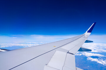 Obraz premium Photo of airplane wing with clouds background, horizon line and clear blue sky