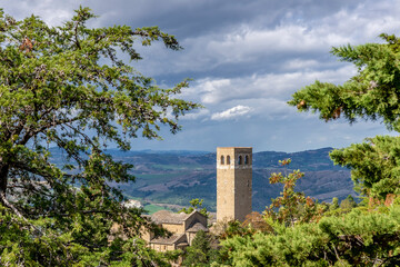 Fototapeta premium The Civic Tower of San Leo, Italy, framed by tree branches, under a dramatic sky