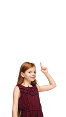 Pointing up, flyer. Happy, smiley little caucasian girl isolated on white studio background with copyspace for ad. Looks happy, cheerful. Childhood, education, human emotions, facial expression