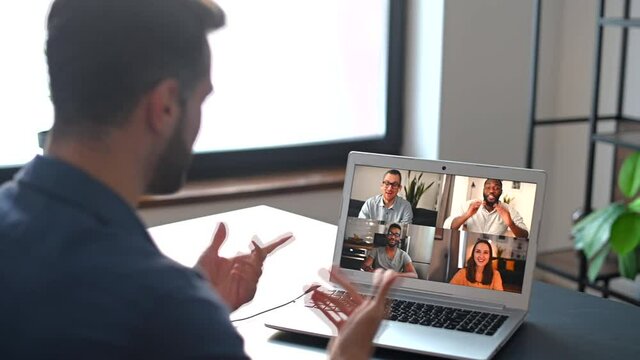 Bearded man in glasses and formal wear using app for distance video communication with coworkers, webinar participants, meeting online in pandemic, looking at the laptop screen with people profiles