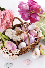 Obraz na płótnie Canvas Easter wicker basket with lamb figurine and colorful eggs