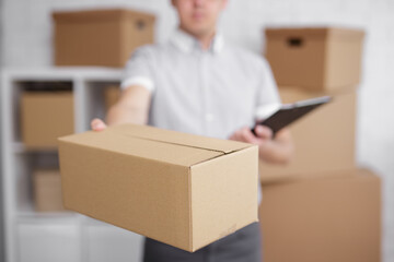 postman with box and clipboard in warehouse or storage