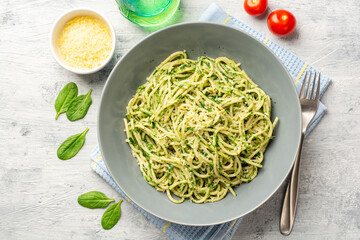 Spaghetti pasta with spinach sauce and parmesan cheese on concrete background