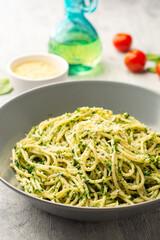 Spaghetti pasta with spinach sauce and parmesan cheese on concrete background