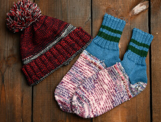 pair of warm comfortable knitted socks and a knitted hat on a brown wooden background