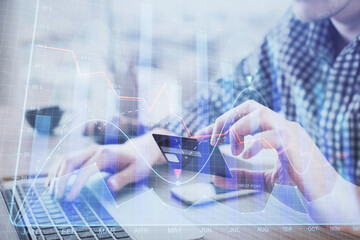 Double exposure of man hands holding a credit card and Forex graph drawing. Stock trading and digital fintech in Internet E-commerce concept.