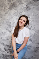 Smiling caucasian woman looking at the camera over gray background. Trendy clothes