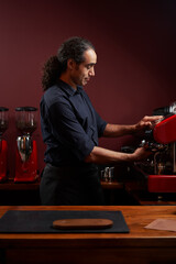 Handsome barista preparing cup of coffee for customer in coffee shop.