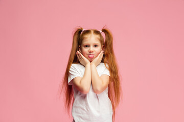 Sticking out tongue. Happy, smiley little caucasian girl isolated on pink background with copyspace for ad. Looks happy, cheerful. Childhood, education, human emotions, facial expression concept.