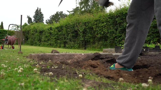 Gardener Digging Trench With Wooden Handled Pickaxe, Low Angle Shot