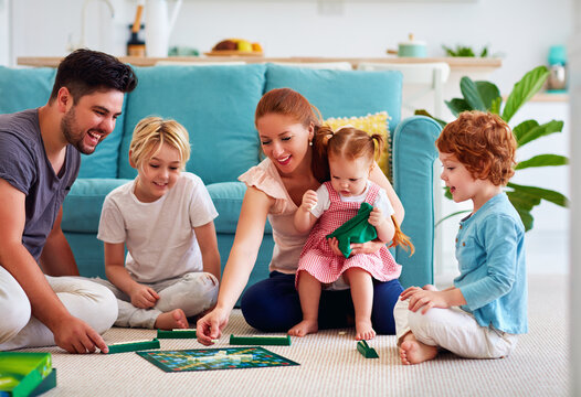 cheerful family having fun, spending time together by playing board games at home