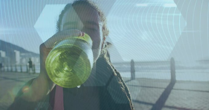 Hexagonal shapes against african american woman drinking water on promenade