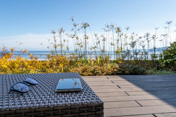 海の見えるバルコニーで過ごすひと時　もしくはテレワーク　イメージ　seaside balcony with smartphone and glasses
