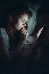 Fototapeta premium woman lies in bed with a phone in her hands emotions relaxation before bed communication