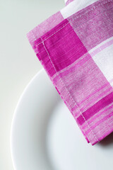 empty white dining plate and pink plaid kitchen towel close up