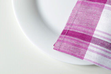 empty white dining plate and pink plaid kitchen towel close up