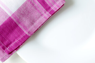 empty white dining plate and pink plaid kitchen towel close up