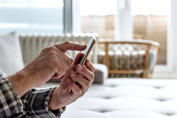 Portrait of modern senior man learning to use smartphone at home in cozy living room. Senior man...