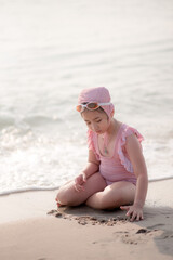Cute asian girl Wearing a pink swimsuit sitting on the beach
