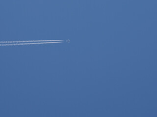 The plane is flies horizontally and leaving traces of a line against the clear blue sky, copy space. Colorful picture with air transport