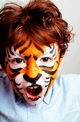 little cute boy with faceart on birthday party close up, little cute tiger