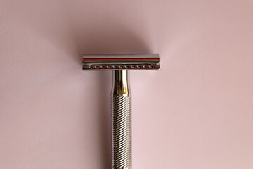 Reusable metal safety razor on pink background. Top view.