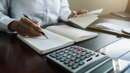 Woman with bills and calculator. Woman using calculator to calculate bills at the table in office....