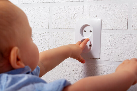 Caucasian boy playing with open electrical outlet.