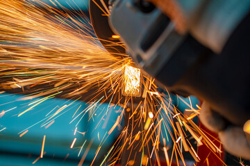 cutting metal pipe grinder in the workshop with sparks on the workbench