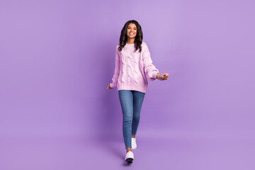 Photo of adorable sweet dark skin woman wear pink sweater smiling walking isolated violet color...
