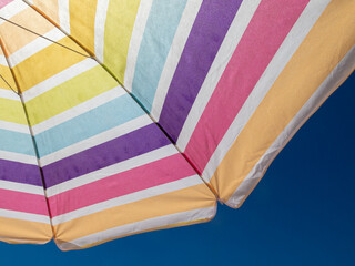 beach umbrella in the summer of spain with multi coloredin a blue sky
