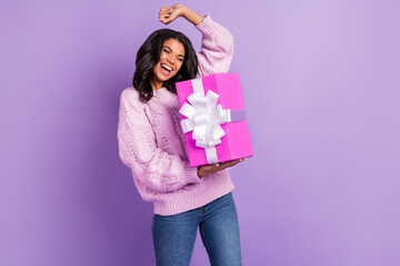 Photo of pretty lucky dark skin lady dressed knitted pullover rising fist getting pink present box isolated purple color background