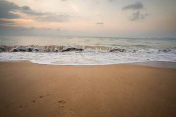 White waves on the beach in the morning, dark tones.