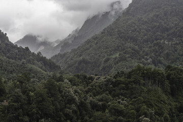 Aerial of the beautiful mountains covered in greens under the cloudy and rainy sky