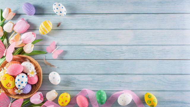 Happy easter! Colourful of Easter eggs in the nest with flower on pastel blue wooden background. Greetings and presents for Easter Day celebrate time. Flat lay ,top view.