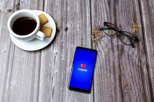 03-03-2021 Portsmouth, Hampshire, UK A mobile phone or cell phone laid on a wooden table with the Lazada shopping app open next to a coffee