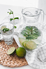 Detox water with lime fruit and mint leaves in jar and glasses