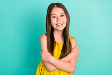 Photo of optimistic nice brown hair girl hug herself wear yellow dress isolated on bright teal color background