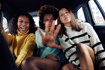 Carefree young women riding together in the backseat of a car