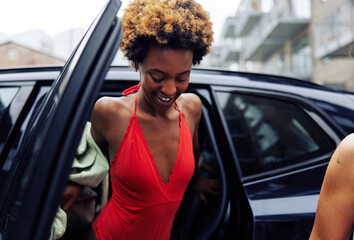 Fototapeta na wymiar Smiling African woman in a swimsuit getting out of a car