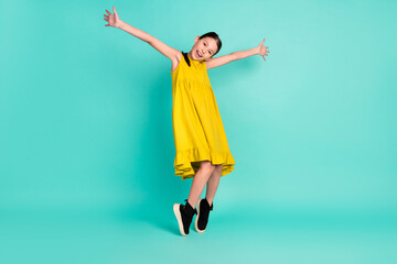 Full size photo of optimistic nice brown hair girl dance wear yellow dress isolated on bright teal color background