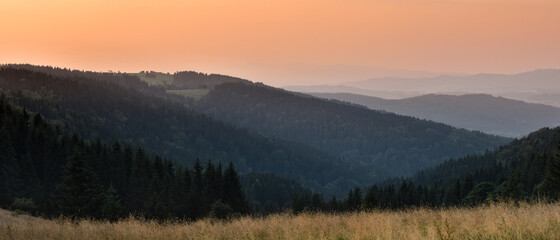 An orange sunset over a mountain range with a gentle fog in the valley.