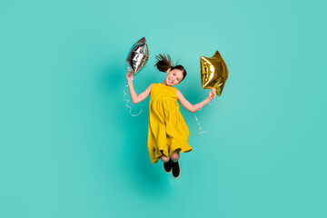 Full size photo of impressed nice brown hair girl hold balloons jump wear yellow dress isolated on bright teal color background