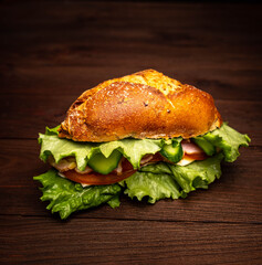 Sandwich with herbs, cheese, tomato and bacon on a wooden background