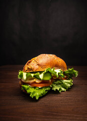 Sandwich with herbs, cheese, tomato and bacon on a wooden background
